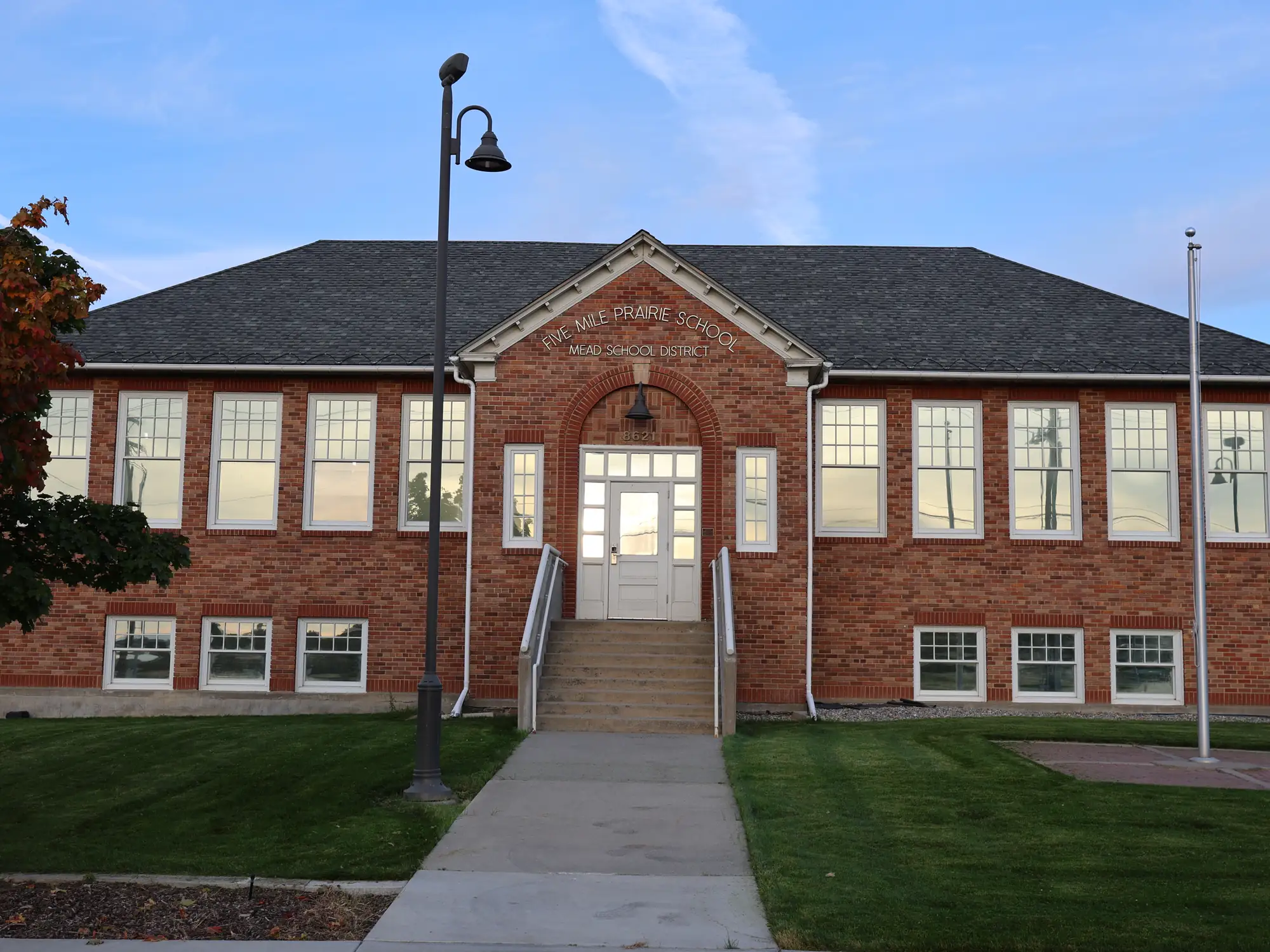 The Spokane site: a two-storey brick schoolhouse with an arched entry, the pediment carved "Five Mile Prairie School".