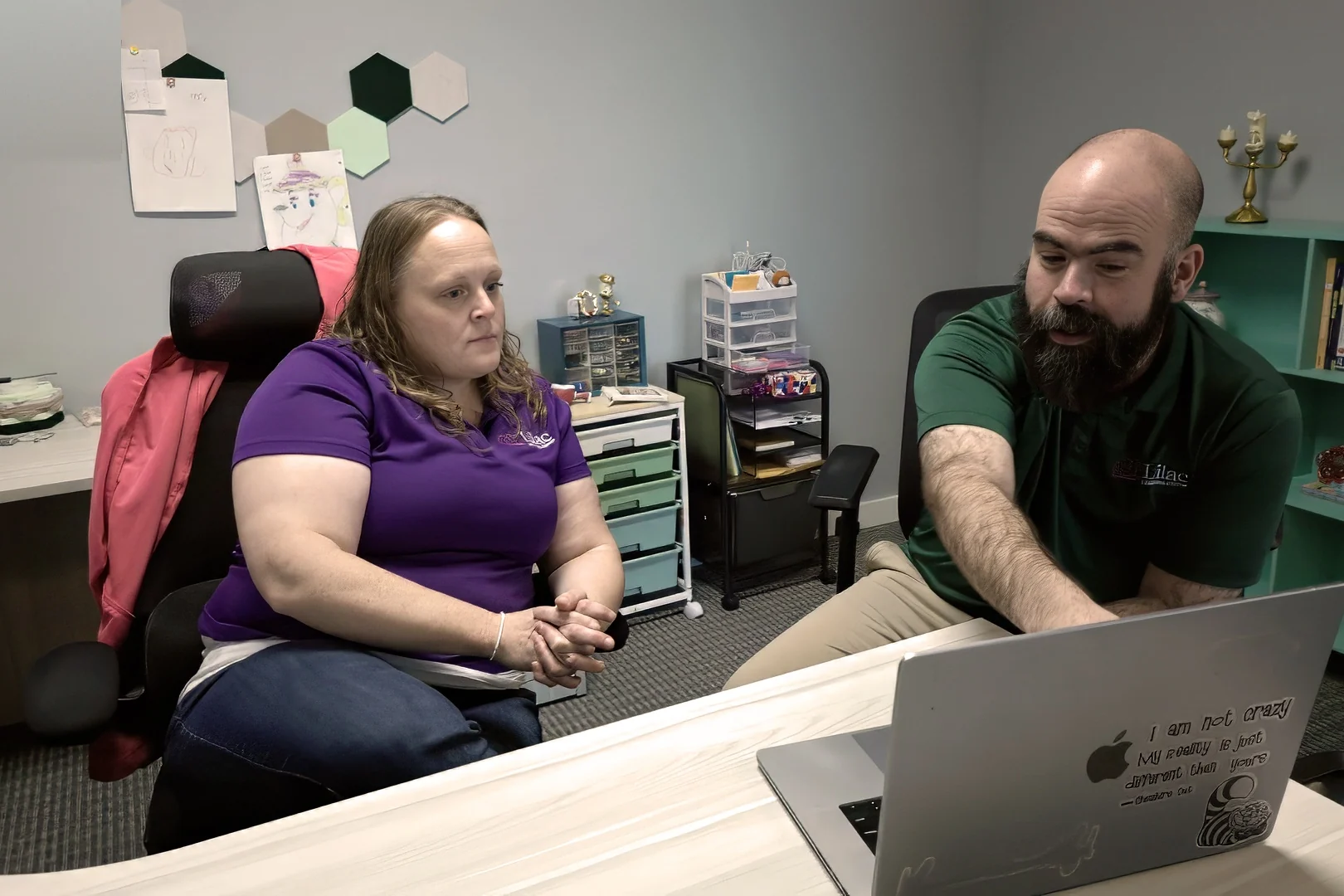 Two Lilac Learning Center staff members sitting together at a desk, looking at a laptop screen.